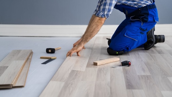 A flooring contractor measuring and laying a new flooring